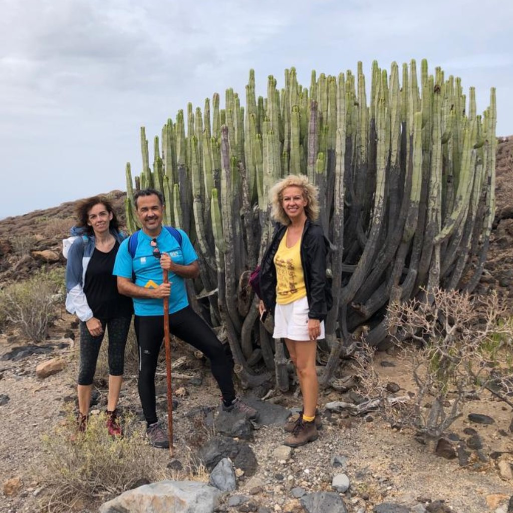 Tre persone accanto a un grande cactus in un ambiente roccioso a Tenerife.