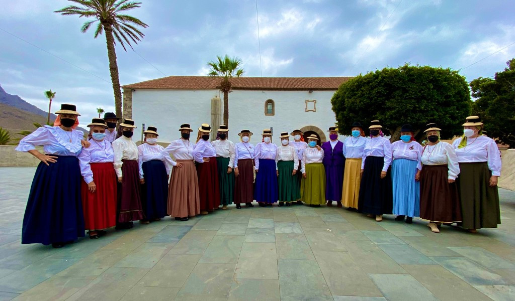 Gruppo di persone in costumi tradizionali a La Gomera, Tenerife, davanti a un edificio.