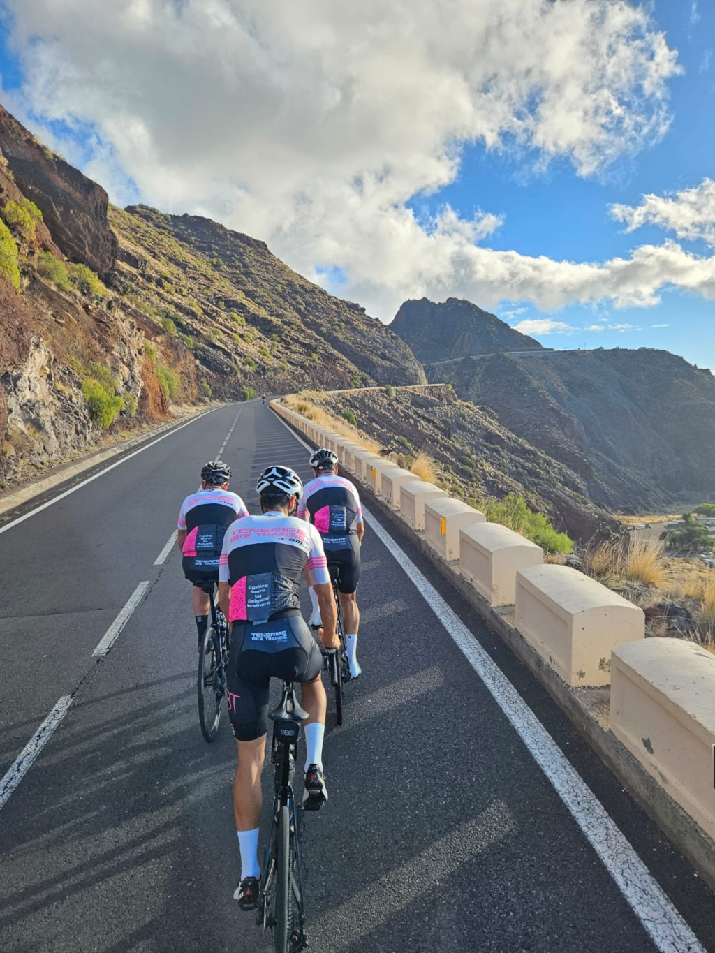 Ciclisti che scalano una strada montuosa a Tenerife sotto cieli parzialmente nuvolosi.