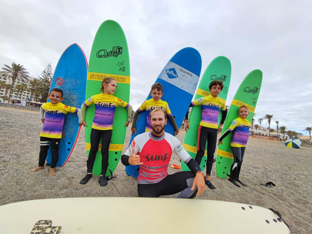 Istruttore di surf con bambini che tengono le tavole sulla spiaggia di Tenerife.