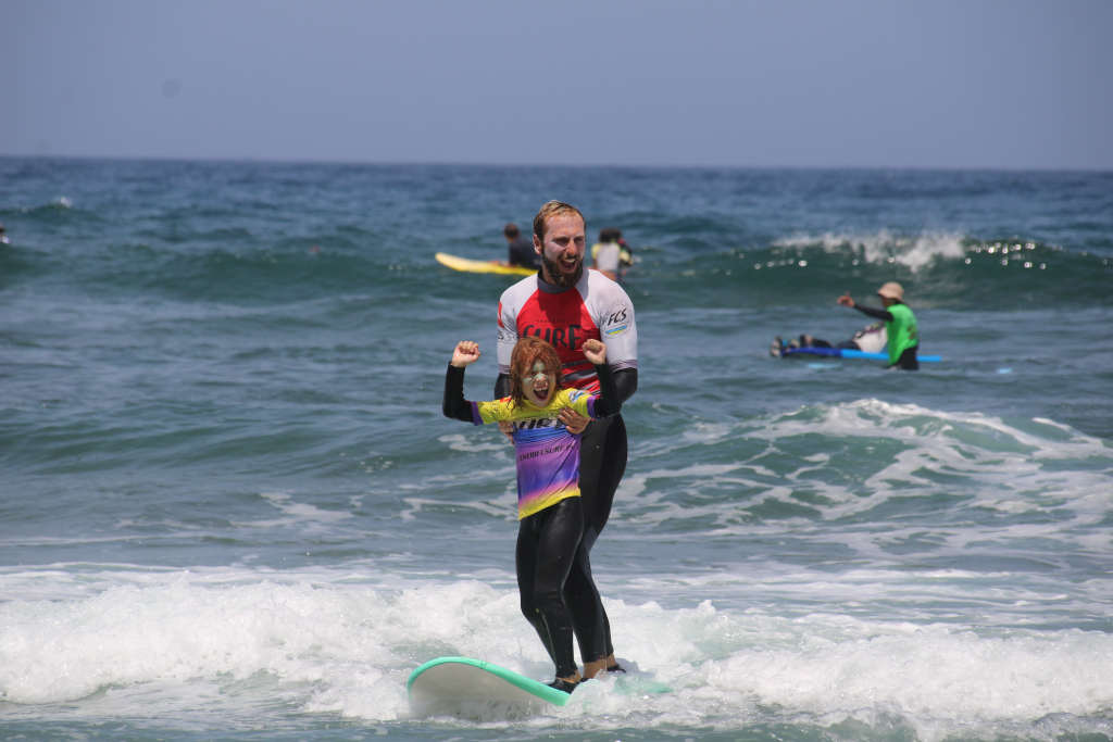 Surfista adulto e bambino in lezione di surf su una spiaggia a Tenerife.