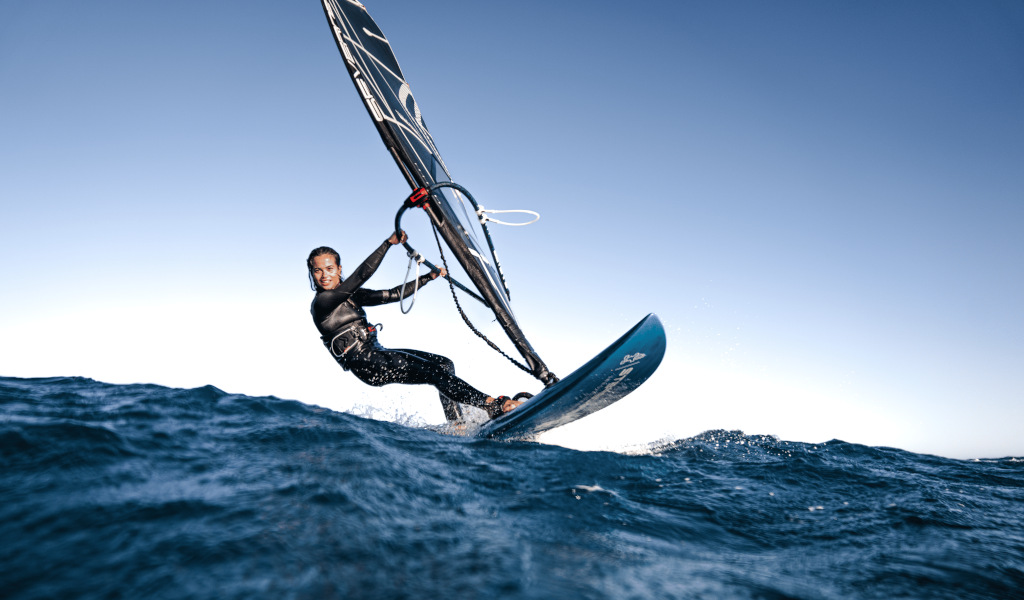 Persona che fa windsurf in mare vicino a Tenerife sotto un cielo limpido.