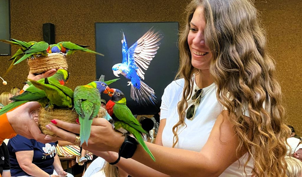 Donna che tiene diversi pappagalli nel Loro Parque a Tenerife.