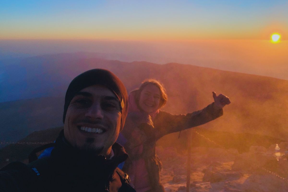 Persone che sorridono all'alba sul Monte Teide, Tenerife, con il sole sullo sfondo.