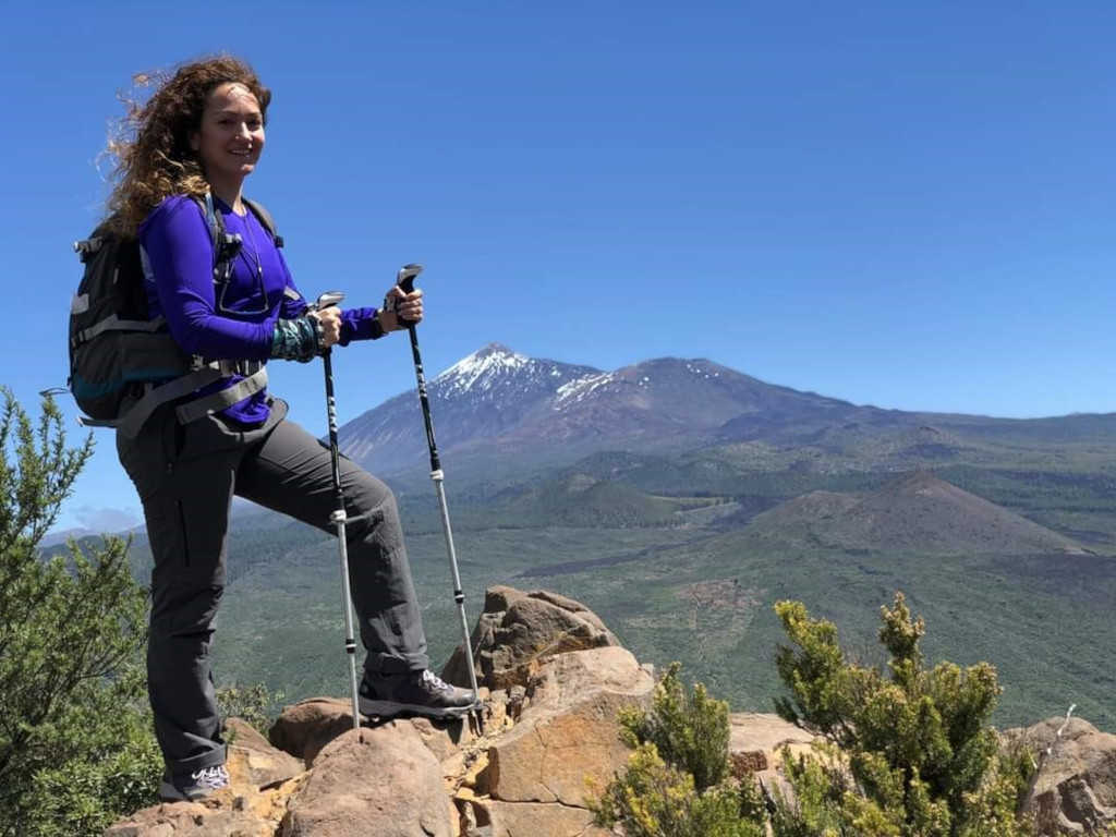 Escursionista con i bastoncini su un sentiero roccioso con il Monte Teide sullo sfondo, Tenerife.