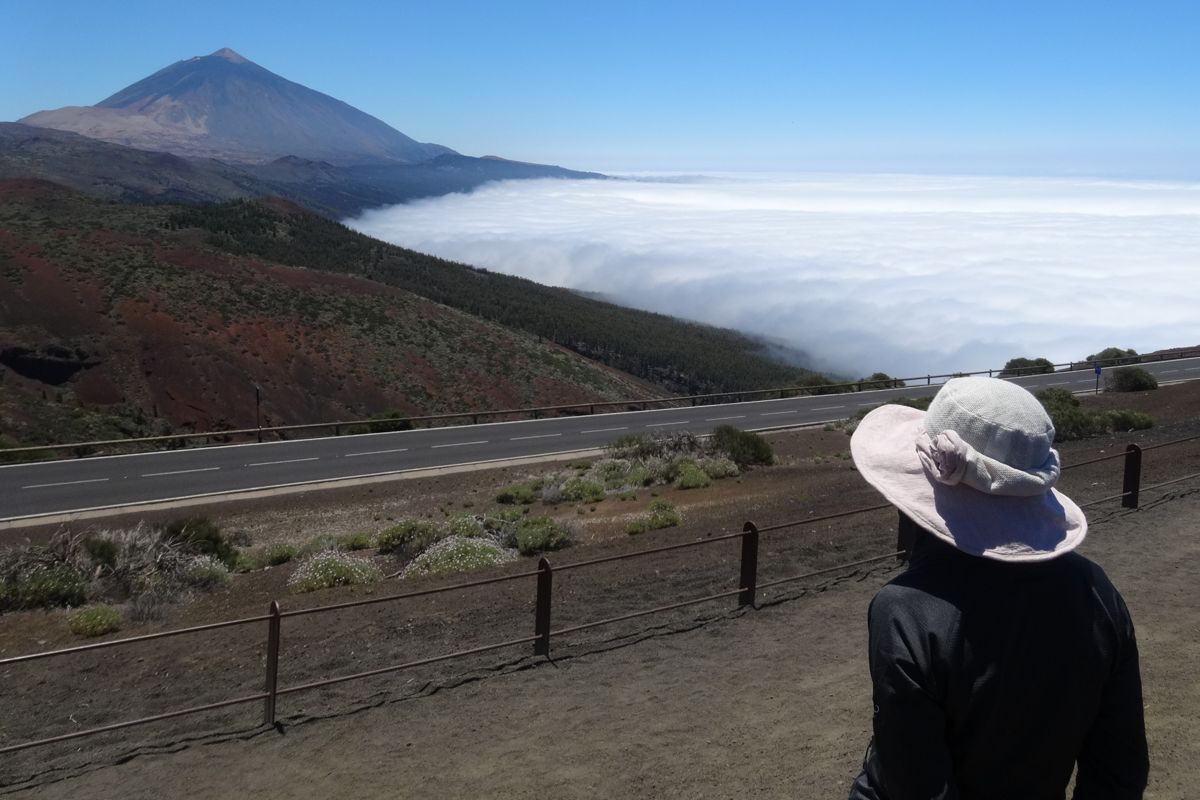 Persona con un cappello che osserva il Teide e il mare di nuvole a Tenerife.