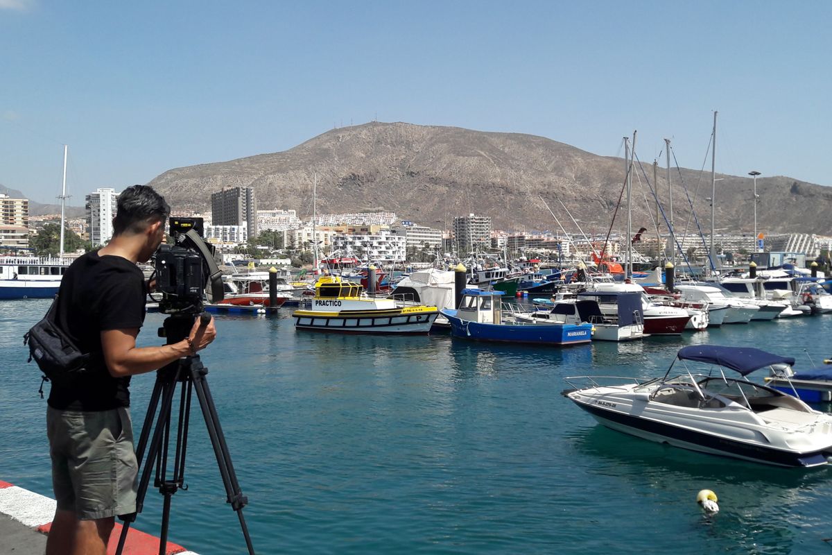 Cameraman che riprende barche nel porto di Los Cristianos, Tenerife.