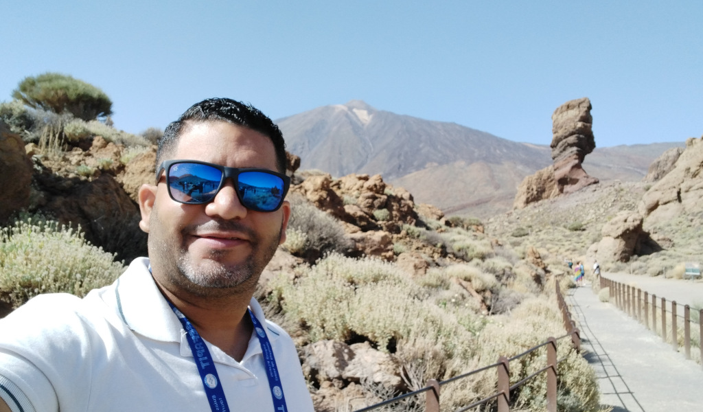 Persona con occhiali da sole nel Parco Nazionale del Teide, Tenerife. Montagna e formazione rocciosa dietro.