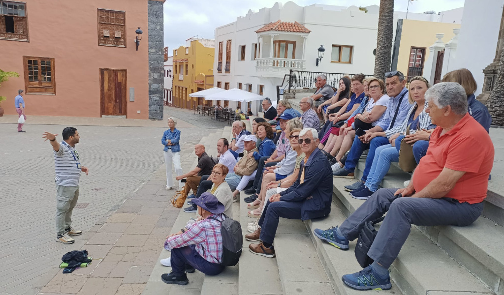 Gruppo di turisti in una piazza a La Laguna, Tenerife, che ascolta una guida turistica.