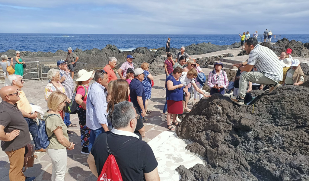 Un gruppo di persone ascolta una guida sulle rocce vulcaniche a Puerto de la Cruz, Tenerife.