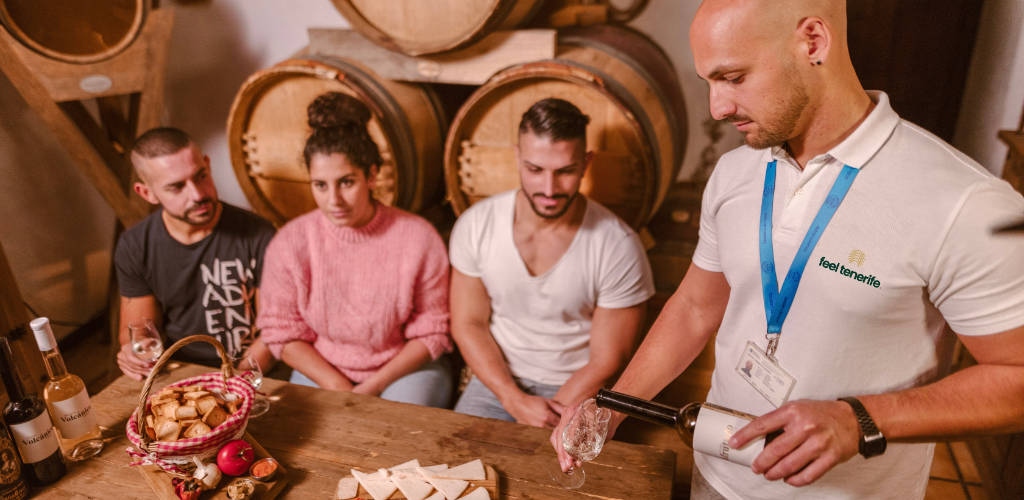 La guida serve vino a tre persone in una cantina a Tenerife.