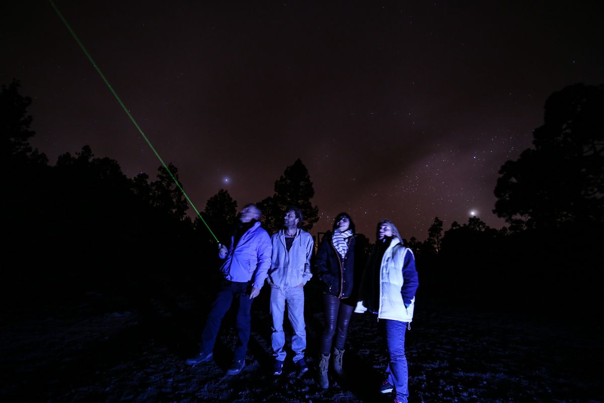 Le persone osservano il cielo stellato a Tenerife, un punto laser verde.
