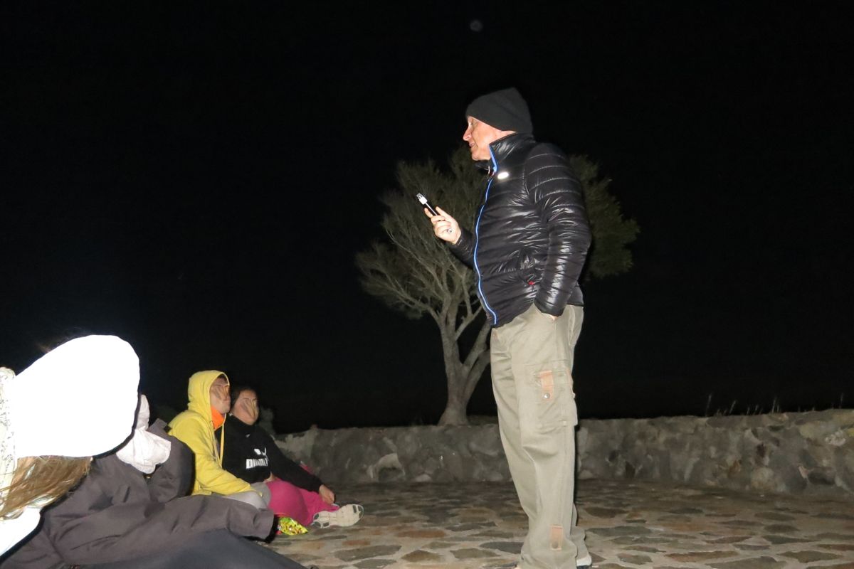 Persona che parla all'aperto di notte a Tenerife, con un gruppo seduto vicino.