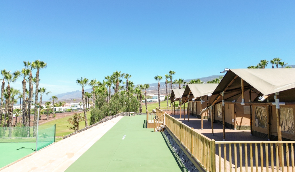 Capanne accanto a palme e montagne in un complesso a Tenerife.
