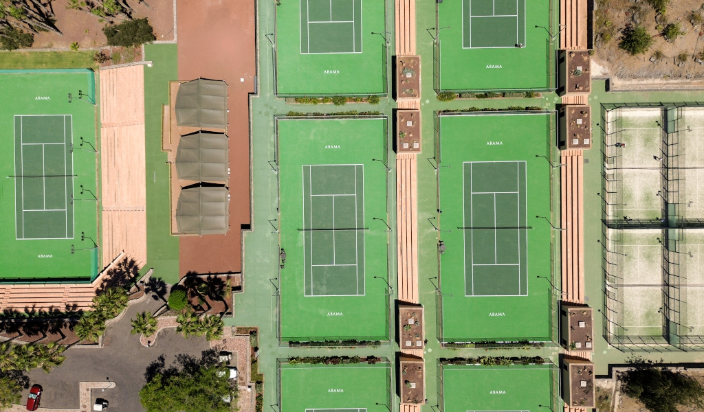 Vista aerea dei campi da tennis ad Abama, Tenerife, circondati da verde e aree di sosta.