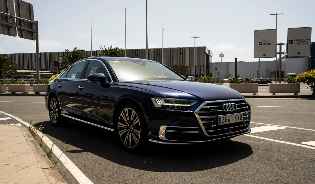 Auto blu parcheggiata davanti all'aeroporto di Tenerife Sud, con il cartello Auto Rental (Auto Noleggio).