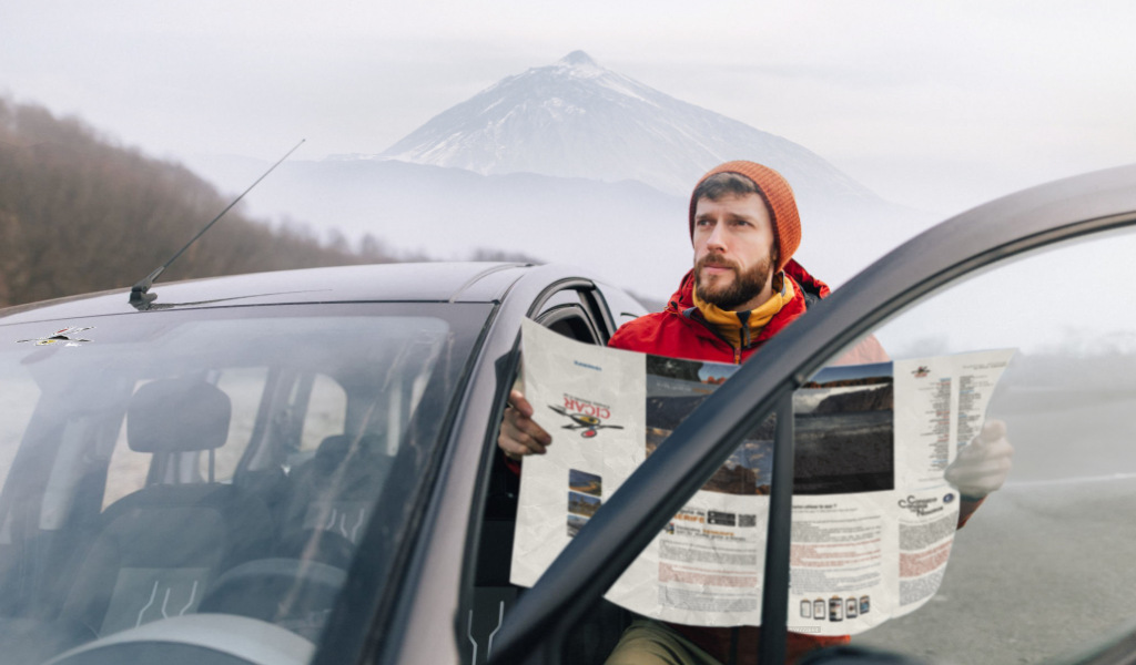 Man consulta una mappa accanto a un'auto con il Monte Teide sullo sfondo, Tenerife.