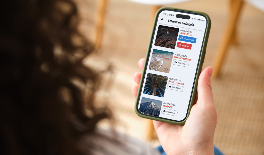 Persona con un cellulare con audioguide di Lanzarote, Fuerteventura, Gran Canaria e Tenerife.