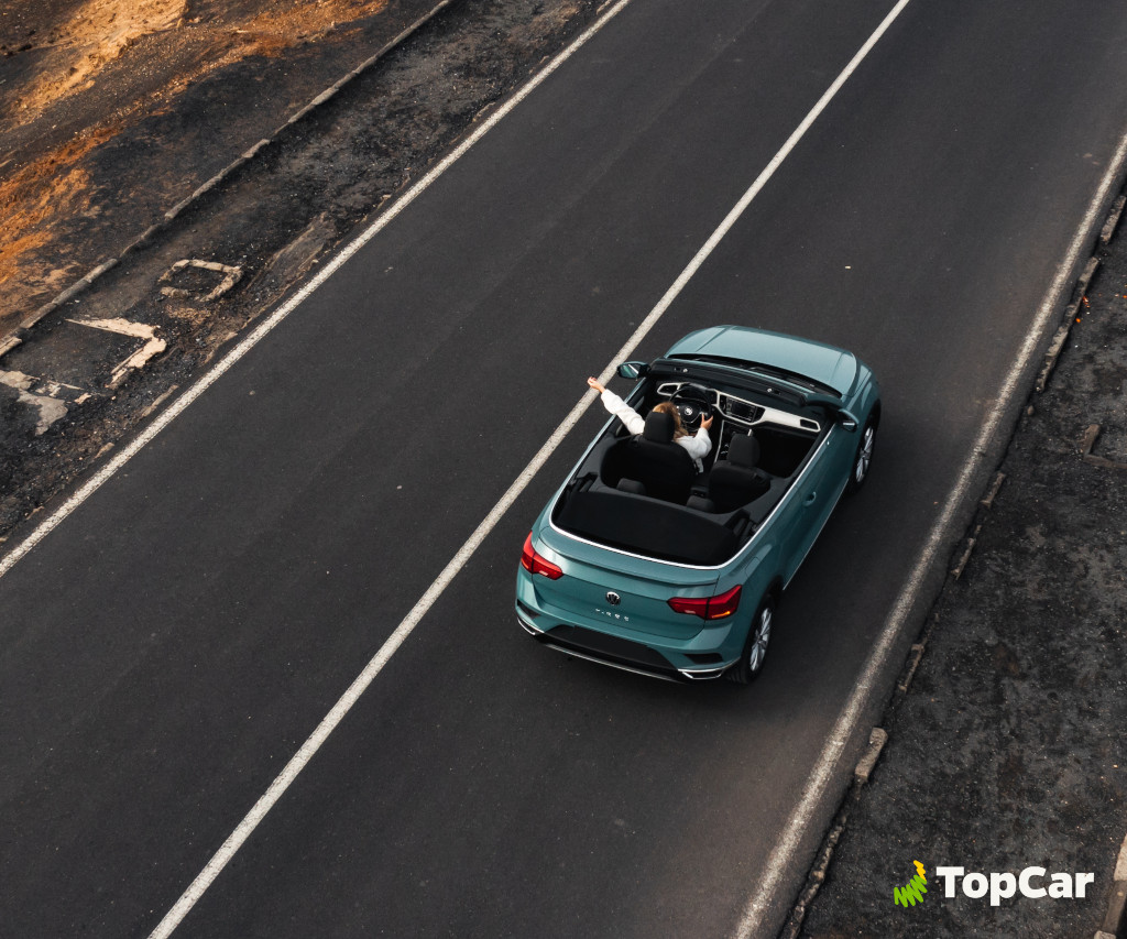 Persona che guida una decappottabile blu sulla strada a Tenerife. Testo visibile: TopCar.