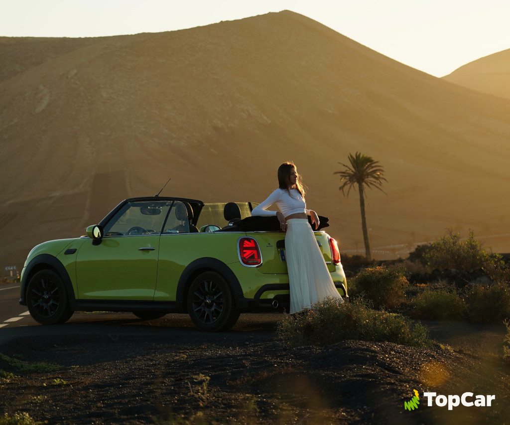 Auto cabriolet verde con persona davanti al paesaggio montuoso di Tenerife.