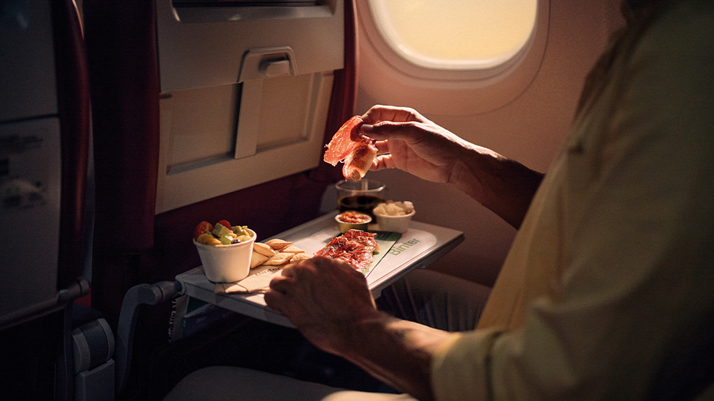 Persona che mangia prosciutto Serrano su un aereo sopra la rivista Turner.
