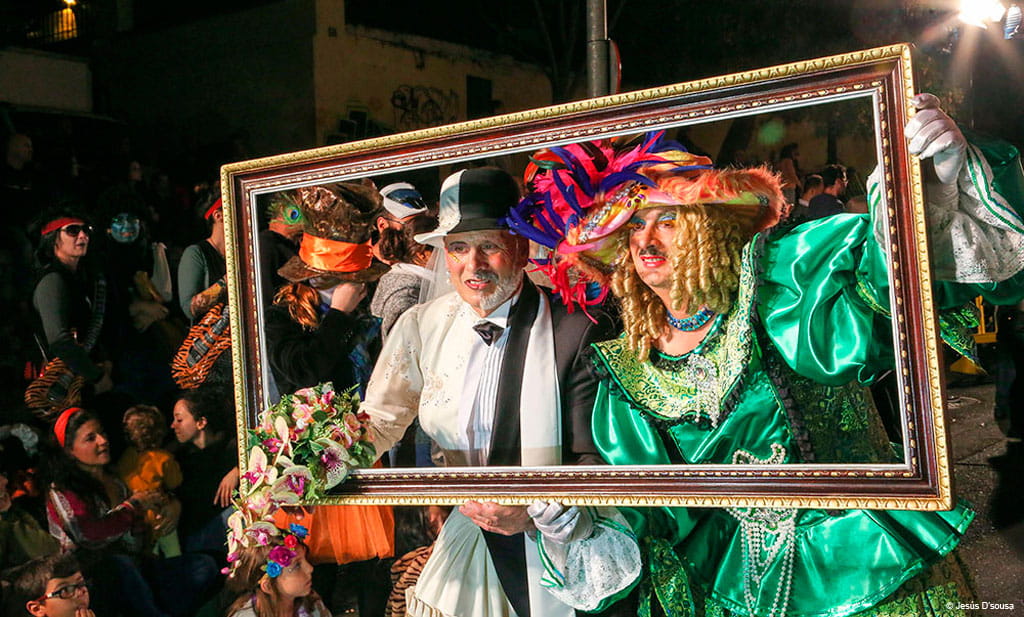 Persone in costumi colorati posano dietro una cornice al carnevale di Tenerife.