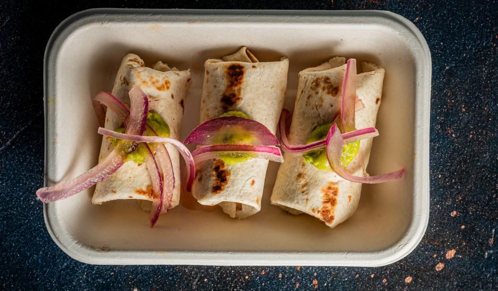 Tre burritos con cipolla rossa e salsa verde su un piatto rettangolare a Tenerife.