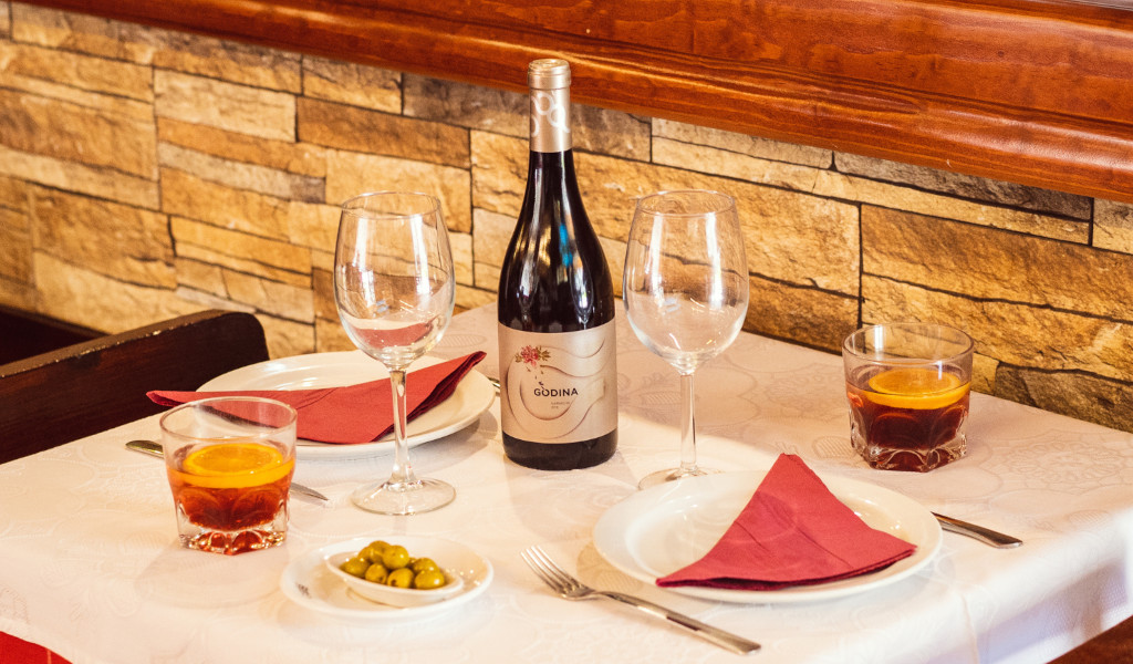 Tavolo in un ristorante a Tenerife con bicchieri, bottiglia di vino gondola e bicchieri con bevande.