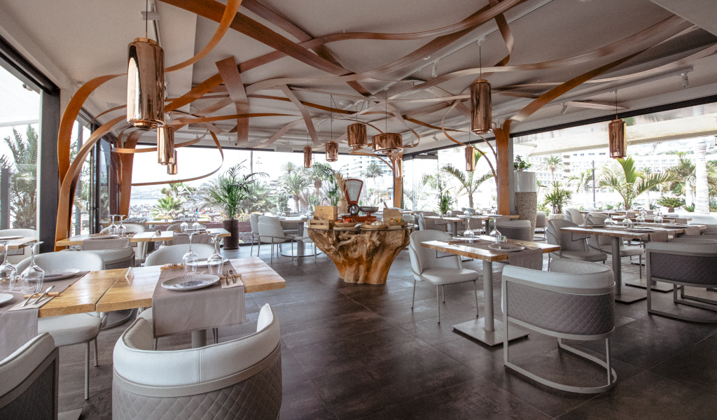 Ristorante moderno con eleganti arredamenti a Tenerife, tavoli disposti vicino a grandi finestre.