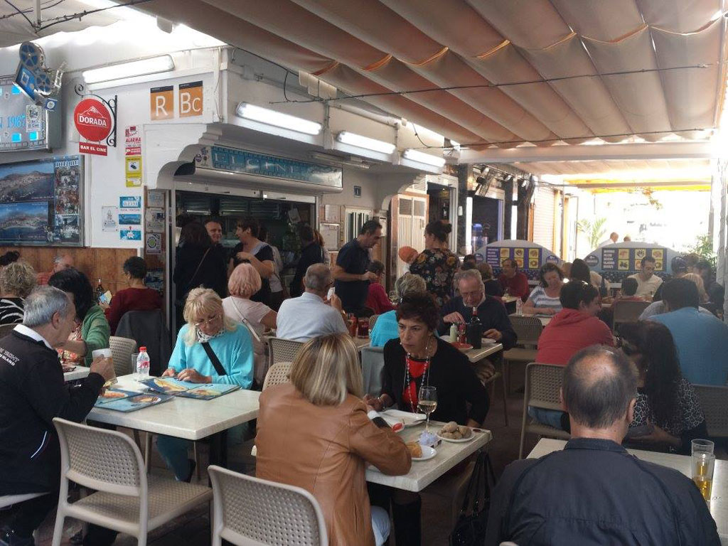 Persone che cenano in un ristorante a Tenerife, con menu e decorazioni visibili.