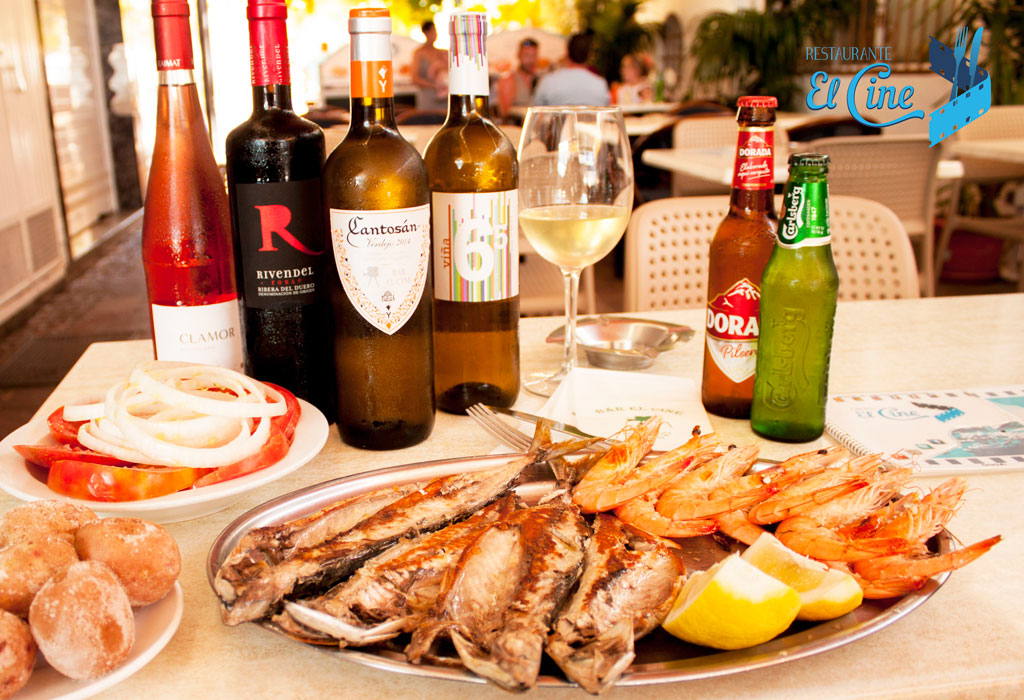 Piatto di pesce e gamberi con bottiglie di vino e birra al ristorante El Cine, Tenerife.