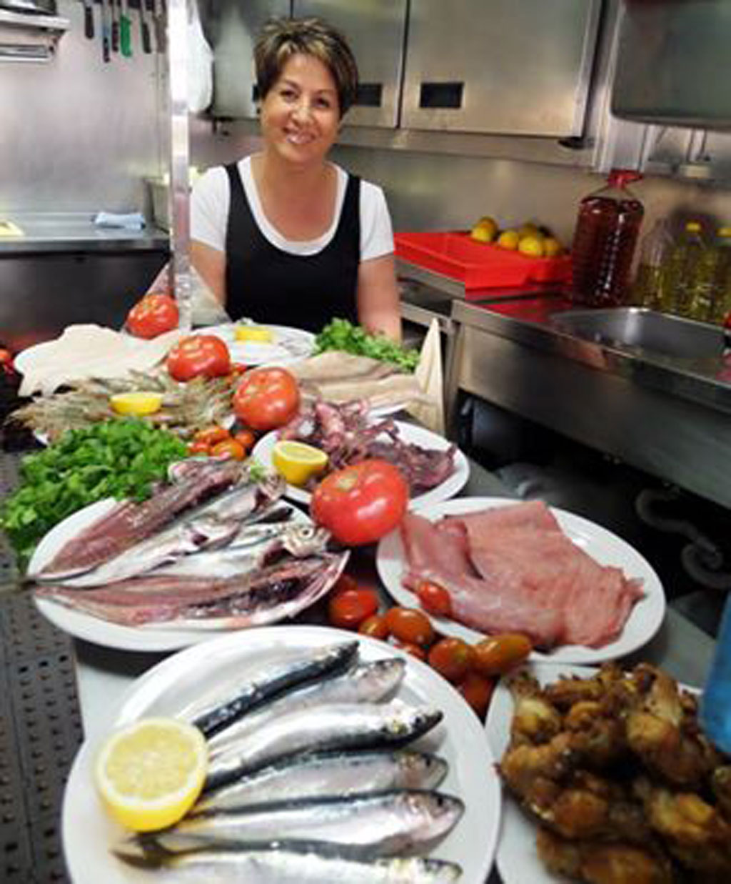 Persona in cucina con piatti di pesce, pomodoro e limone a Tenerife.