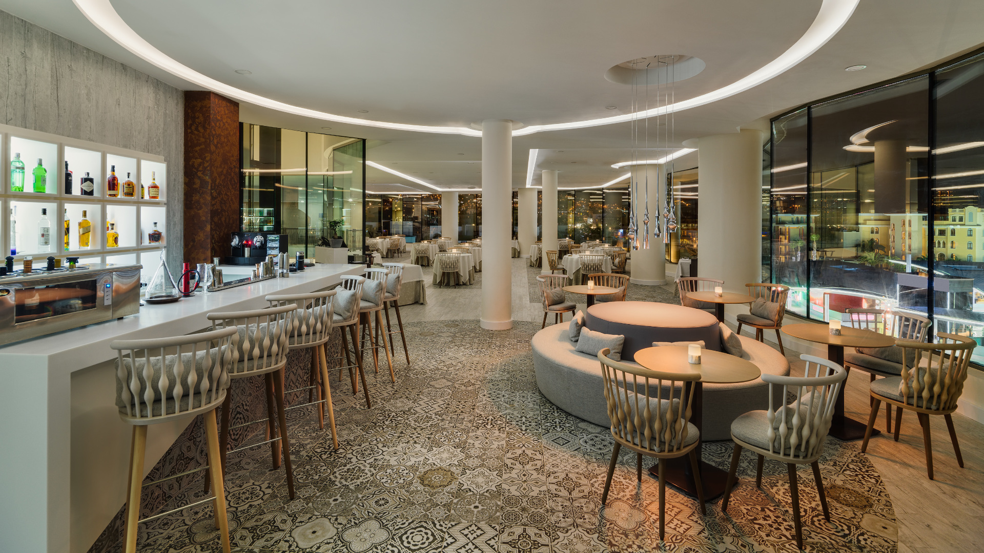 Interno di un elegante ristorante a Tenerife, con un bar illuminato e tavoli con sedie.