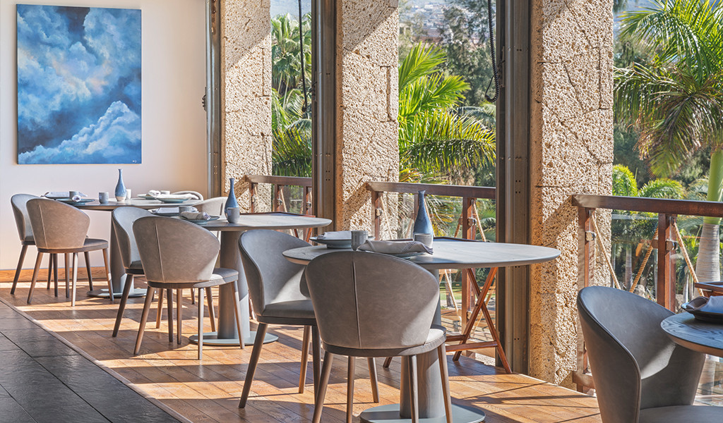 Sala da pranzo con tavoli e sedie accanto a grandi finestre che si affacciano sui giardini di Tenerife.