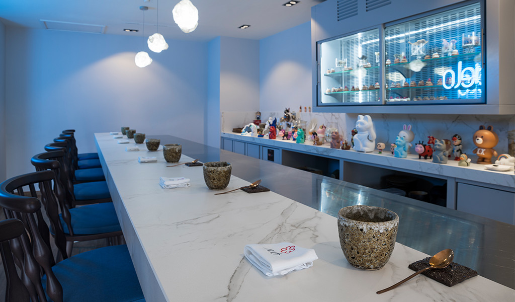 Sushi bar con decorazioni a forma di figure e sedie blu in un ristorante a Tenerife.
