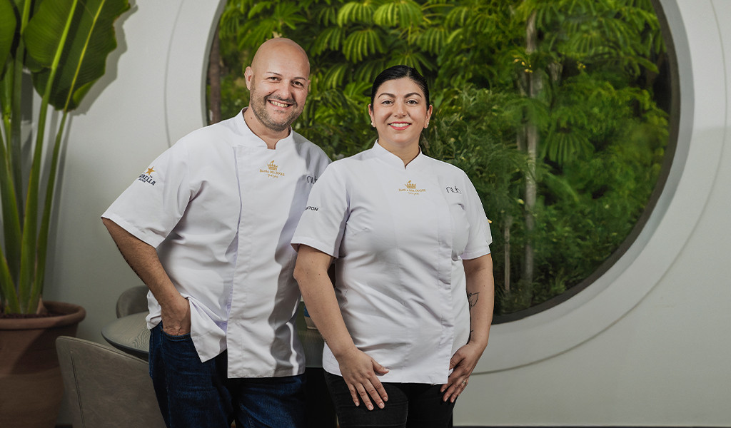 Due chef che sorridono in uniformi bianche davanti a un giardino a Tenerife.