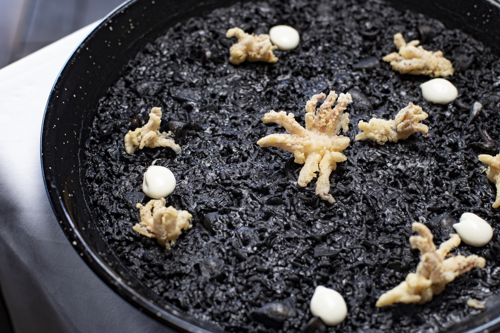 Riso nero con calamaro e aioli serviti in piatto a Tenerife.