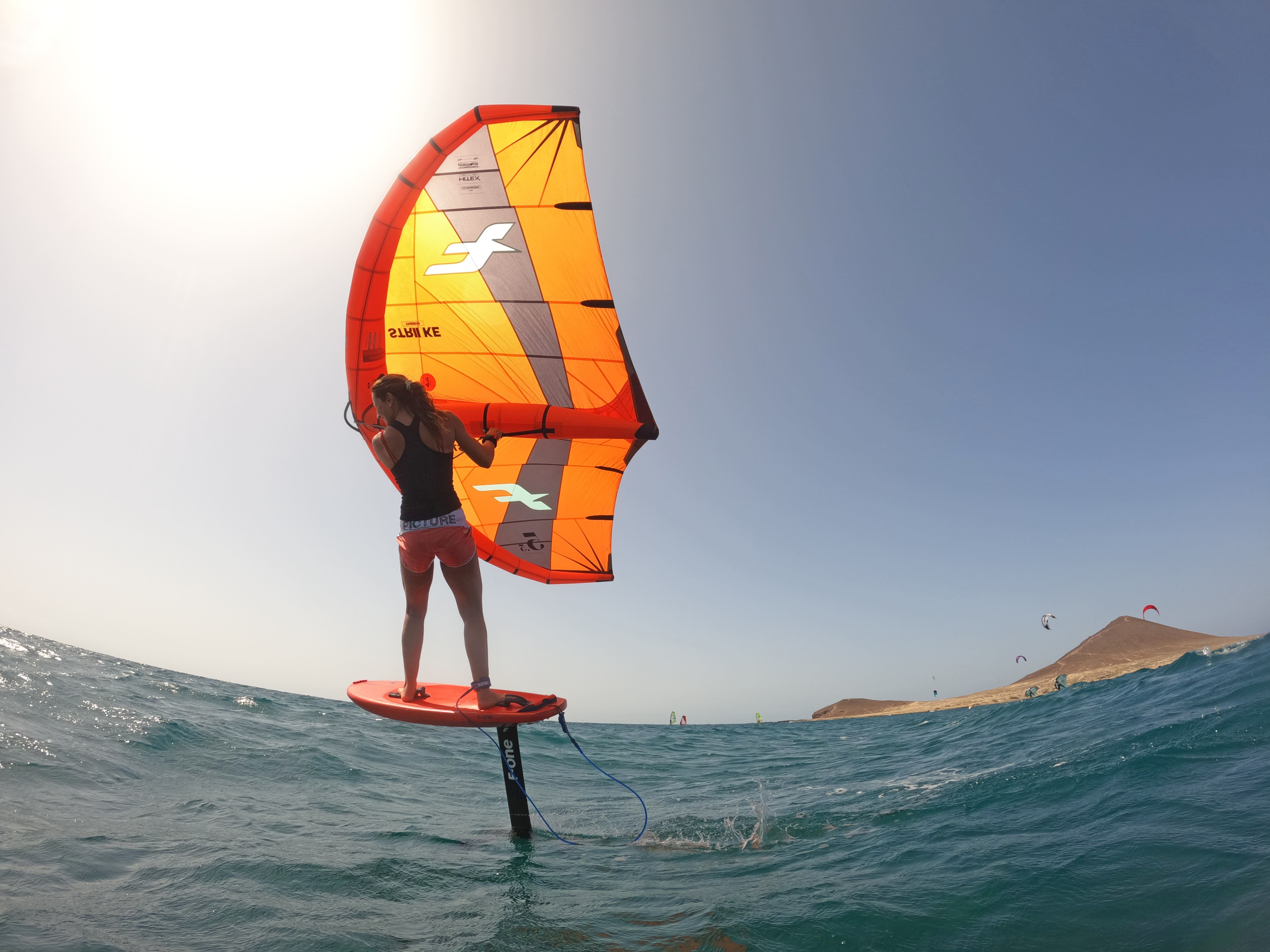 Persona che pratica il wing foiling in mare vicino alla spiaggia di El Médano, Tenerife.