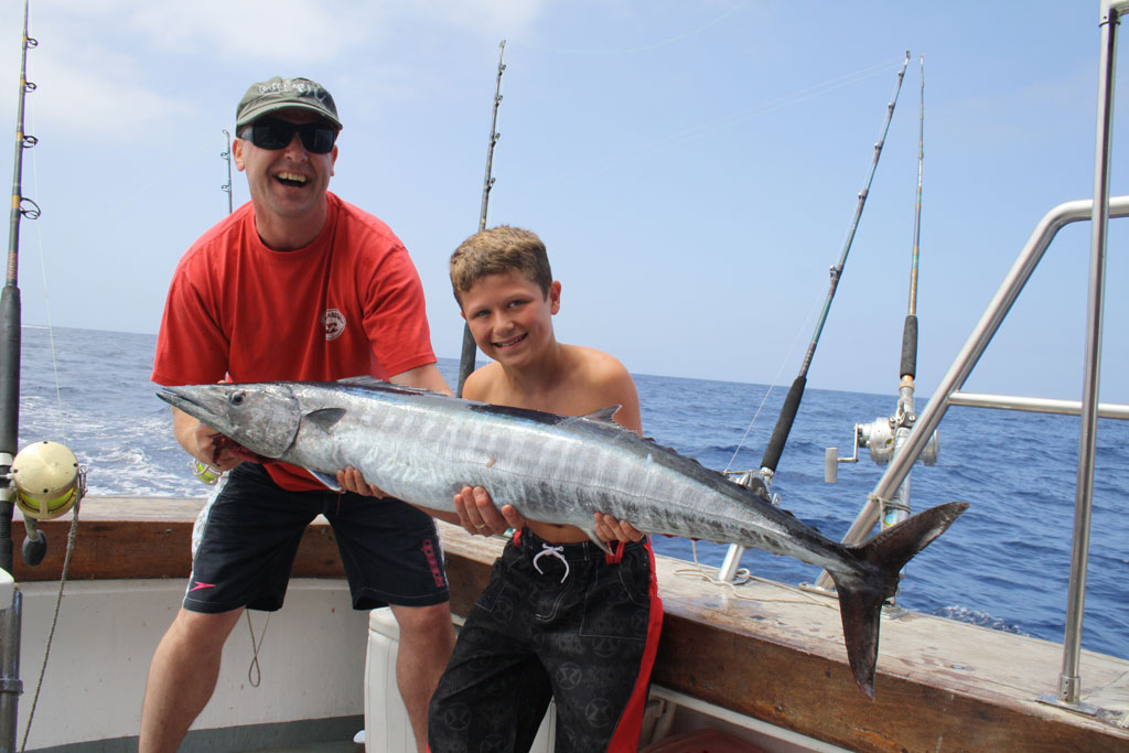 Persone che tengono un grosso pesce su una barca da pesca a Tenerife.