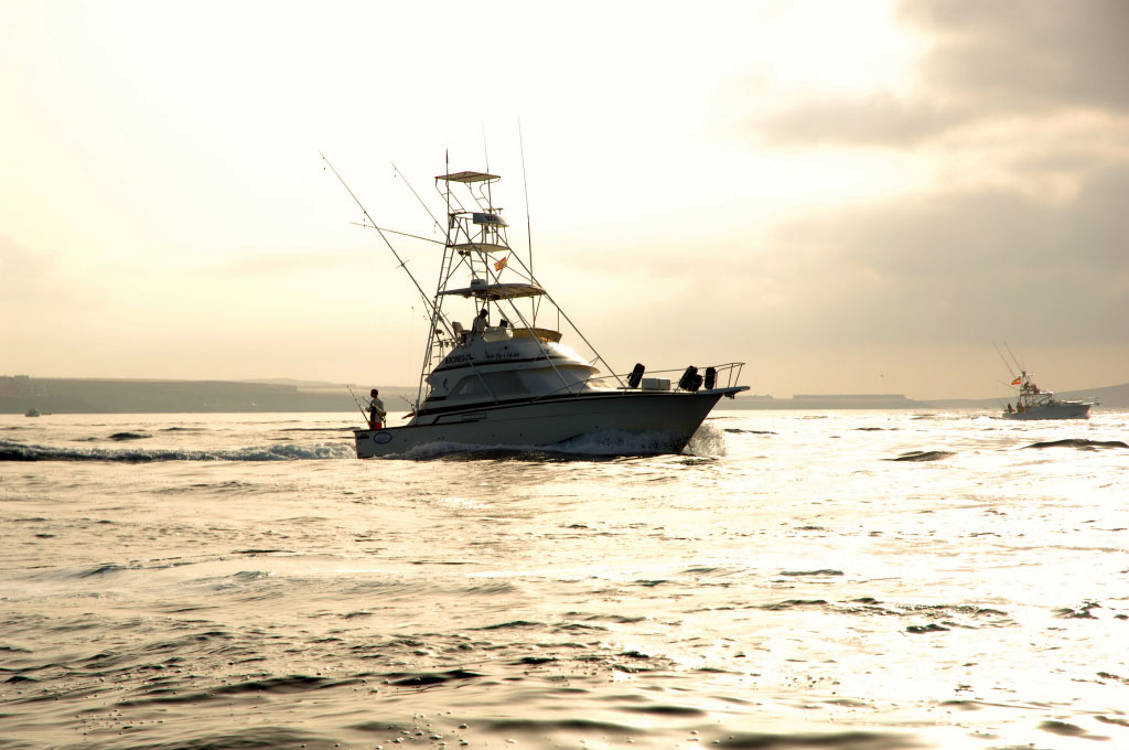 Barca da pesca che naviga al tramonto vicino alla costa di Tenerife.