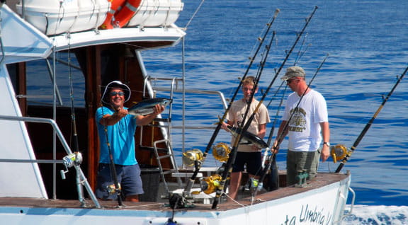 Persone che pescano in barca nelle acque di Tenerife con un pesce appena pescato.
