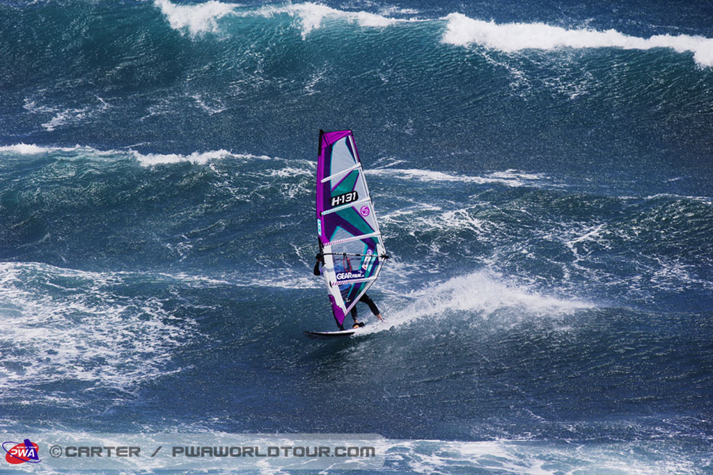 Persona che fa windsurf sulle onde giganti a Tenerife. Testo visibile: H13