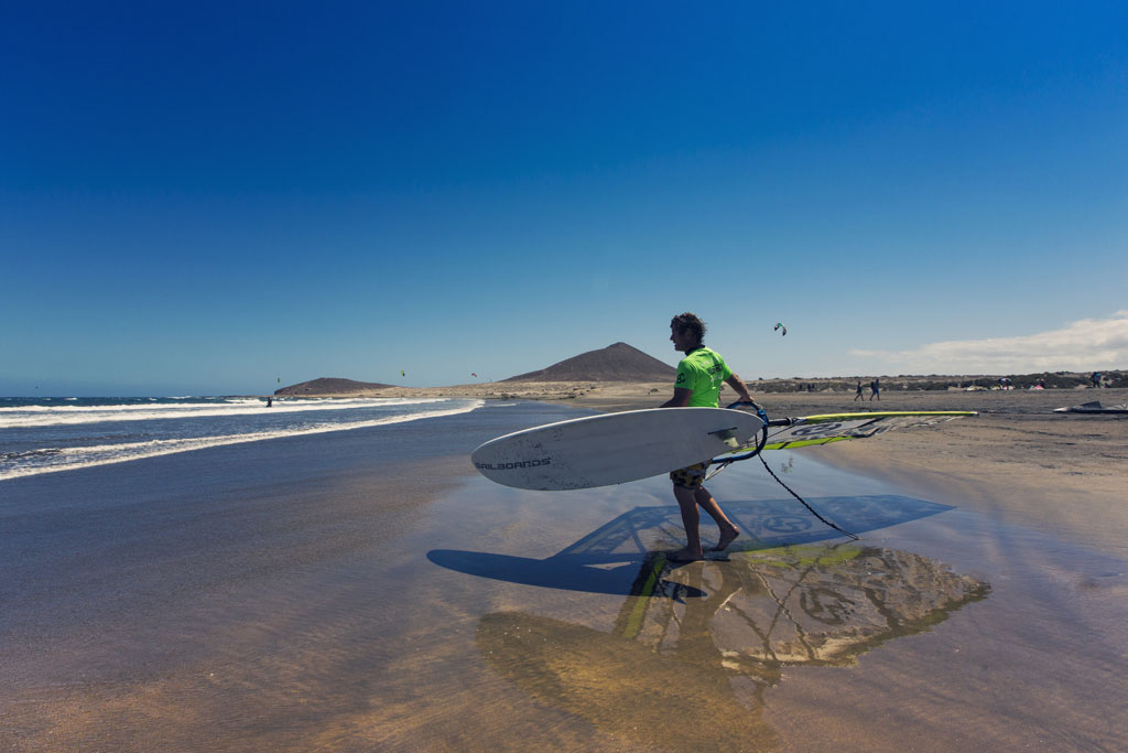 Persona con tavola da windsurf sulla spiaggia di El Médano, Tenerife.
