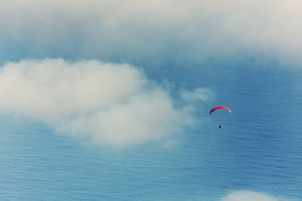 Parapendio sull'oceano a Tenerife tra nuvole sparse.