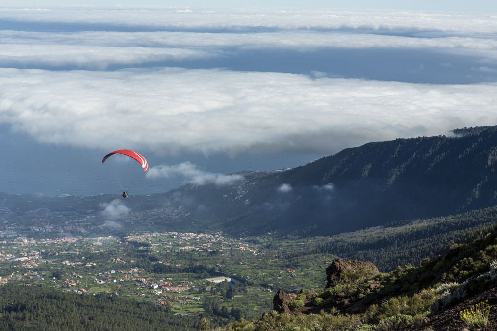 Parapendio che sorvola la valle a Tenerife con nuvole basse.