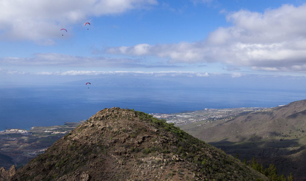 Parapendii che sorvolano una montagna a Tenerife che domina l'oceano.