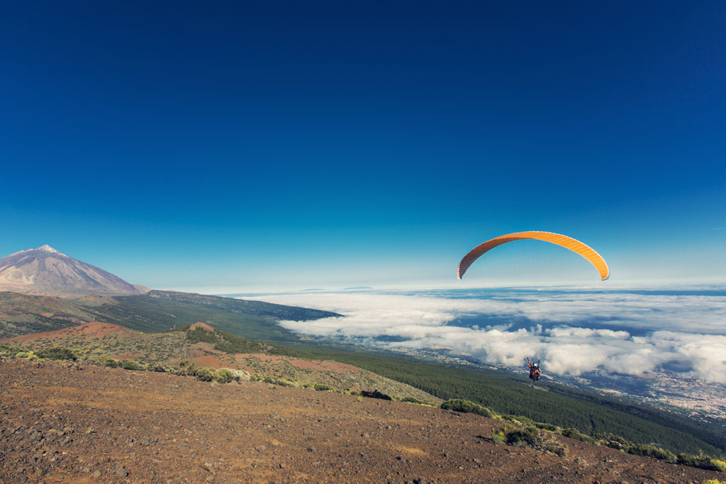 Parapendio in volo vicino al Monte Teide a Tenerife sotto cieli limpidaggi.