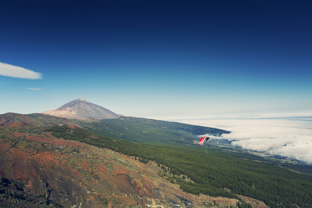 Parapendio sul Monte Teide a Tenerife, con nuvole e paesaggio vulcanico.