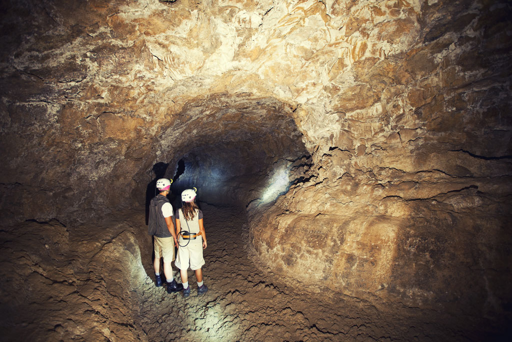 Esploratori con elmetti attraversano un tunnel a Cueva del Viento, Tenerife.