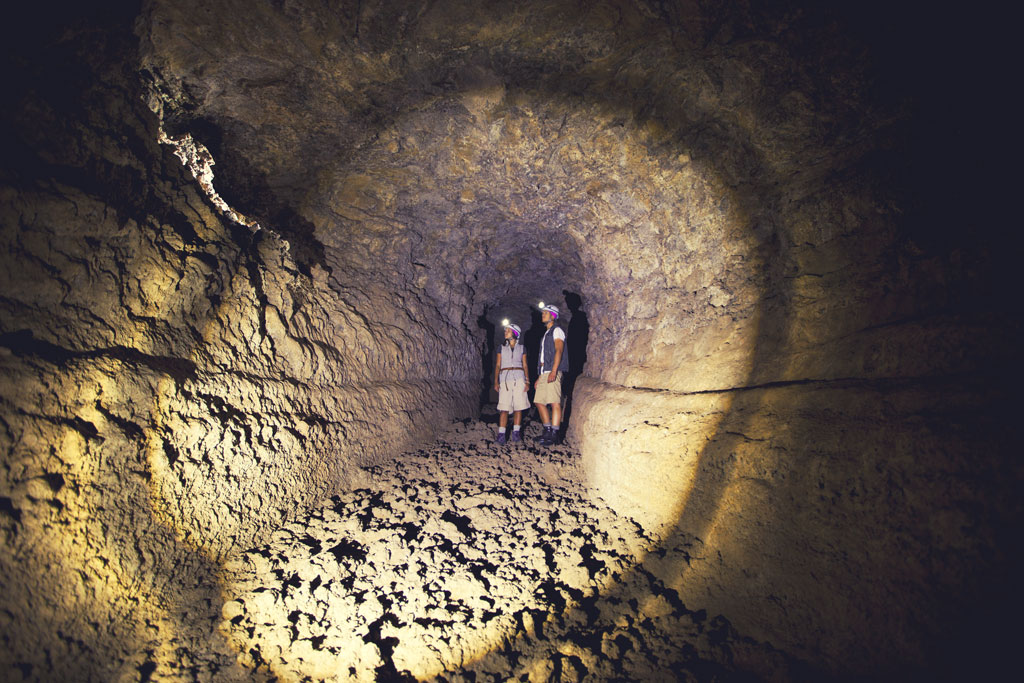 Esploratori con torce in un tunnel vulcanico a Tenerife.